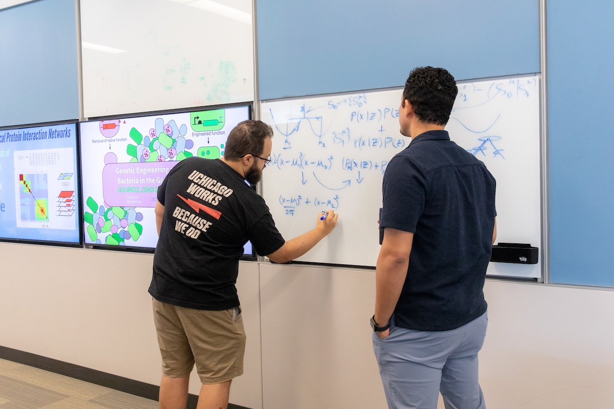 University of Chicago classroom where two men are writing an equation on a white board